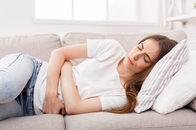 Woman with Stomach Ache Laying on Couch Recover From a Binge