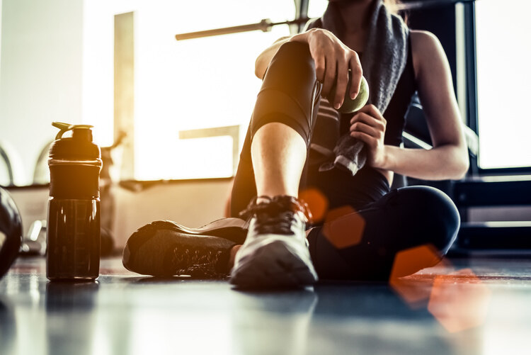 Sport woman sitting and resting after workout or exercise in fitness gym with protein shake or drinking water on floor. Fit for Free Picture