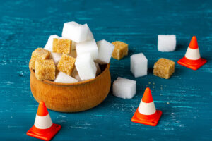Lots Of Granulated Sugar. Sugar In A Wooden Bowl. Traffic Cones and a blue background. Added Sugar