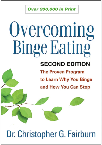 The cover for the book Overcoming Binge Eating by Dr. Christopher Fairburn is shown. It has the title in navy blue letters and says below: Second Edition, The Proven Program to Learn Why You Binge and How You Can Stop. The cover is white with a picture of a tree branch and green leaves.